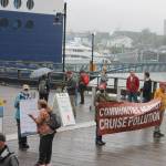 Members of the Juneau Cruise Action Network hold signs as they advocate for more cleaner cruise operations on the piers downtown on July 26, 2022. (Clarise Larson / Juneau Empire)