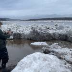 2. Ryan Becker, a teacher at the Eagle school, takes a photo of the toppled Front/Lincoln Street sign after Yukon River ice overtopped the town’s seawall on the morning of May 13, 2023. Photo by Ned Rozell.