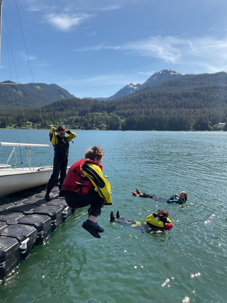 Angus Andrews, 14, jumps into the water during a Juneau Youth Sailing course with Kaia Mangaccat, 13, Lua Mangaccat, 15, and Sigrid Eller, 13, this week near the Juneau Yacht Club. (Therese Pokorney / Juneau Empire)