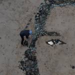Blake Byers places rocks along the outline of a models face being recreated on Sandy Beach in early November. (Photo by Blake Byers)