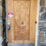 Original visitor entry door to the Mendenhall Glacier Visitor Center with totemic legend design carved in 1961 by architect Steve Forrest, son of lead architect Linn Forrest Sr. (Photo by Laurie Craig)