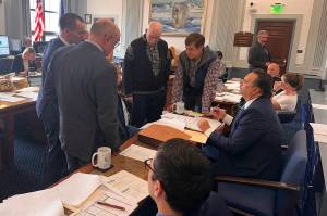 Legislators and staff huddle to discuss adjustments to a final compromise spending plan during a budget conference committee meeting on Sunday at the Alaska State Capitol. (Mark Sabbatini / Juneau Empire)