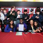 Juneau-Douglas High School: Yadaa.at Kalé senior Ahmir Parker, center, signed a letter of intent Thursday in the JDHS commons to attend Waldorf University in Forest City, Iowa, and play soccer for the Viking Warriors. Among teammates are. family members, seated from left, Parkers maternal grandmother Michelle Monts, mother Kelli Patterson, Ahmir Parker, grandmother Sherry Patterson and little sister Makaylah Patterson. (Klas Stolpe / Juneau Empire)