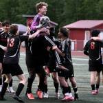 Juneau-Douglas High School: Yadaa.at Kalé Crimson Bears freshman goalkeeper Callen Walker (1) is swarmed by teammates after saving the final shot in a penalty shootout win over Service to open the 2025 ASAA/First National Bank Alaska Soccer State Championships at Wasilla High School on Thursday, May 29, 2025. Senior teammate Kellen Chester (8) consoles Service senior Matej Omalley (2). (Klas Stolpe / Juneau Empire)