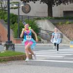 Cianna Kahl as the Mad Hatter and Morgan Adams as Alice sprint to the finish line on Friday, June 20, 2025. (Natalie Buttner / Juneau Empire)