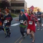 Runners cross Willoughby Avenue on Friday, June 20, 2025. Leading the pack are Adeline Souza and Heather Jones dressed as Mrs. Roper from the 1970s sitcom Threes Company. They were inspired by the nationwide phenomenon Mrs. Roper Romps. (Natalie Buttner / Juneau Empire)