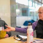Lori Stedman (right) hands out a National Oceanic and Atmospheric Administration Weather Alert Radio provided by the Juneau Lions Club to those attending a Juneau Flood Solution Advocates meeting on Thursday, June 26, 2025. (Jasz Garrett / Juneau Empire)