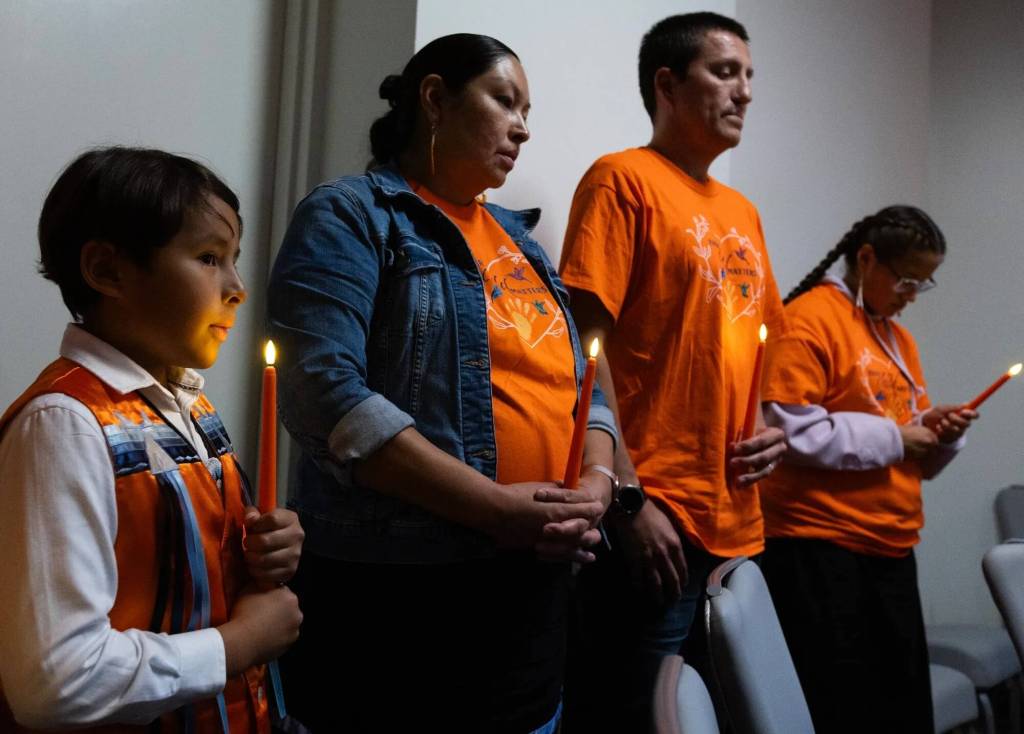 Eight-year-old Floyd Azure Jr. stands with his parents Heather and Floyd Azure during a candlelight vigil as part of a National Day of Remembrance of boarding school survivors and families hosted Tuesday, Sept. 16, 2025, by the National Native American Boarding School Healing Coalition in Washington, D.C. His mother, Heather, attended Flandreau Indian School. (Credit: Charles Fox for ICT)