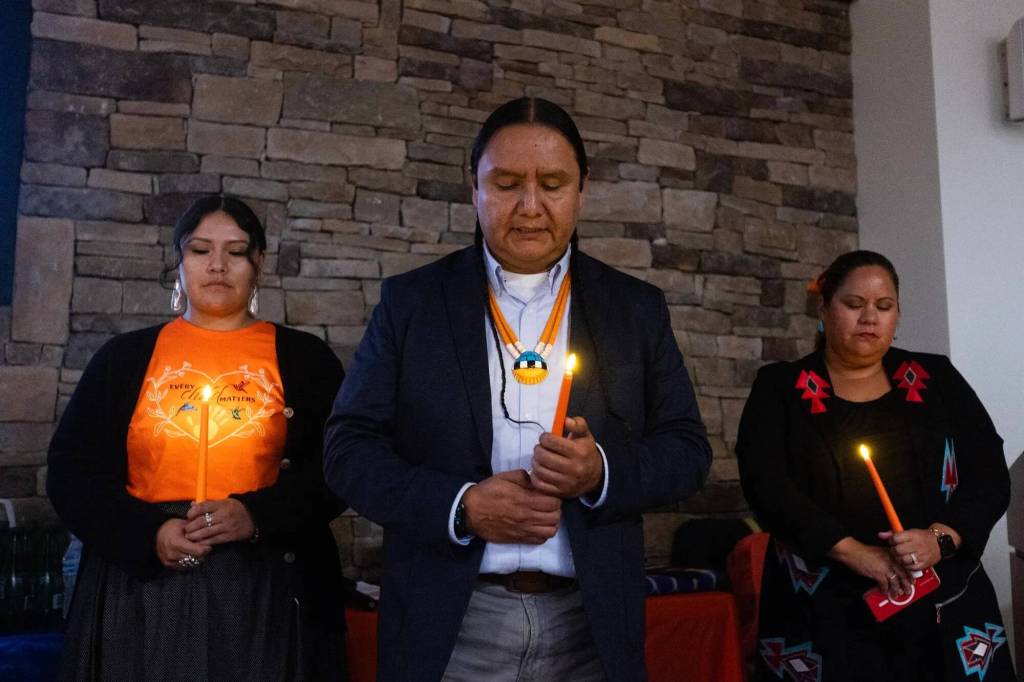 Jason Packineau, center, senior director of strategic initiatives for the National Native American Boarding School Healing Coalition leads a prayer at a National Day of Remembrance Event and candlelight vigil hosted by NABS on Tuesday, Sept. 16, at the Indian Gaming Association in Washington, D.C. They honored U.S. Indian boarding school survivors and the children who never returned home. (Credit: Charles Fox for ICT)