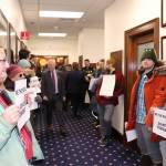 Protesters wait for Sullivan to arrive at the chamber, holding signs that read We The People // Do Not Consent.