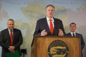 Gov. Mike Dunleavy speaks about new Trump administration policies at a news conference Wednesday, Jan. 22, 2025, in his Anchorage office. Behind him are Attorney General Treg Taylor and Department of Natural Resources Commissioner John Boyle. (Yereth Rosen/Alaska Beacon)