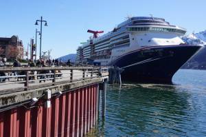 Tourists walk along Juneaus harbor on April 26, 2024, next to the docked Carnival Spirit, a ship operated by Carnival Cruise Line. (Yereth Rosen/Alaska Beacon)