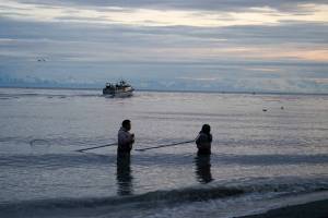 Fishers stand at the mouth of the Kasilof River in Kasilof, Alaska, on June 25, 2025. (Jake Dye/Peninsula Clarion file photo)